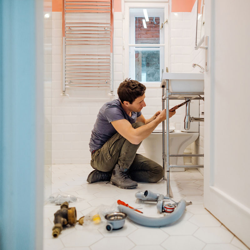 master plumber uses tools to fix pipes in bathroom